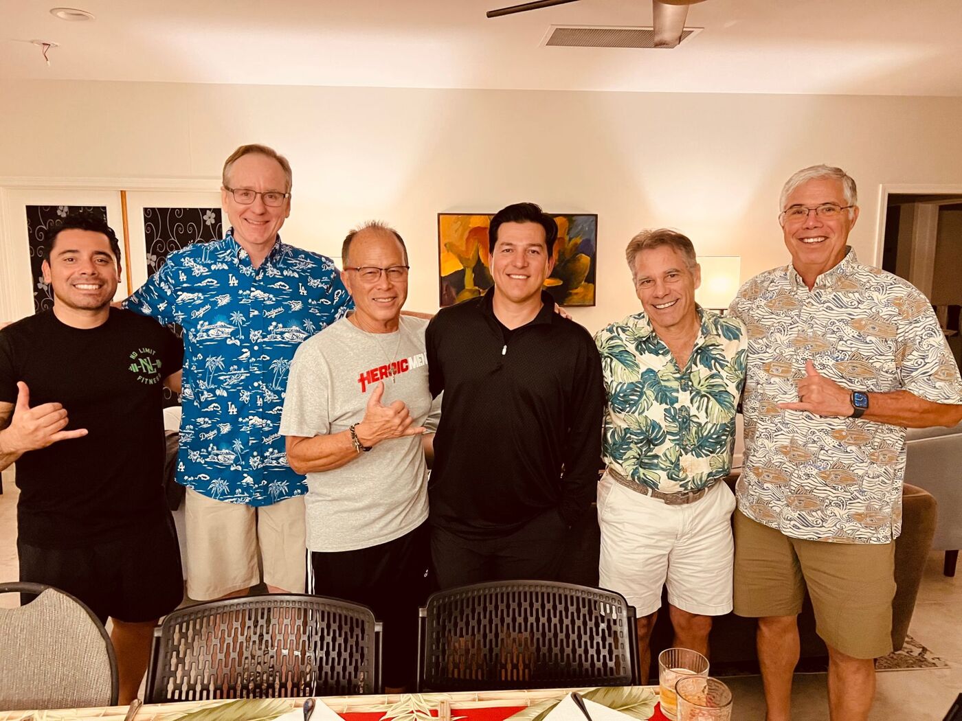 Six men of the fellowship at a dinner, several giving the shaka